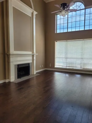 an empty room with wooden floor fireplace and windows