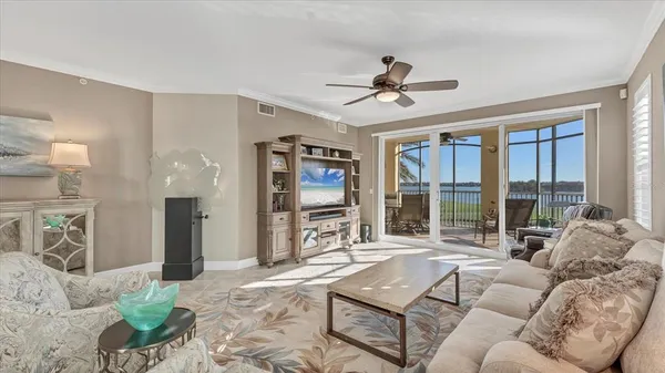 a living room with furniture a ceiling fan a lamp and a window