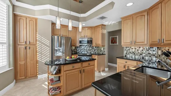 a kitchen with granite countertop a sink and a white wooden cabinets
