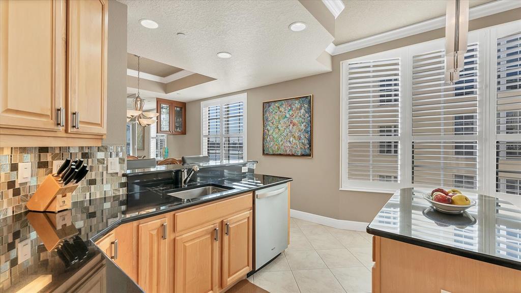 6414 Water Crest Way, Unit 302 Lakewood Ranch, FL 34202 - Photo 25 of 74 a kitchen with granite countertop a sink and a white wooden cabinets