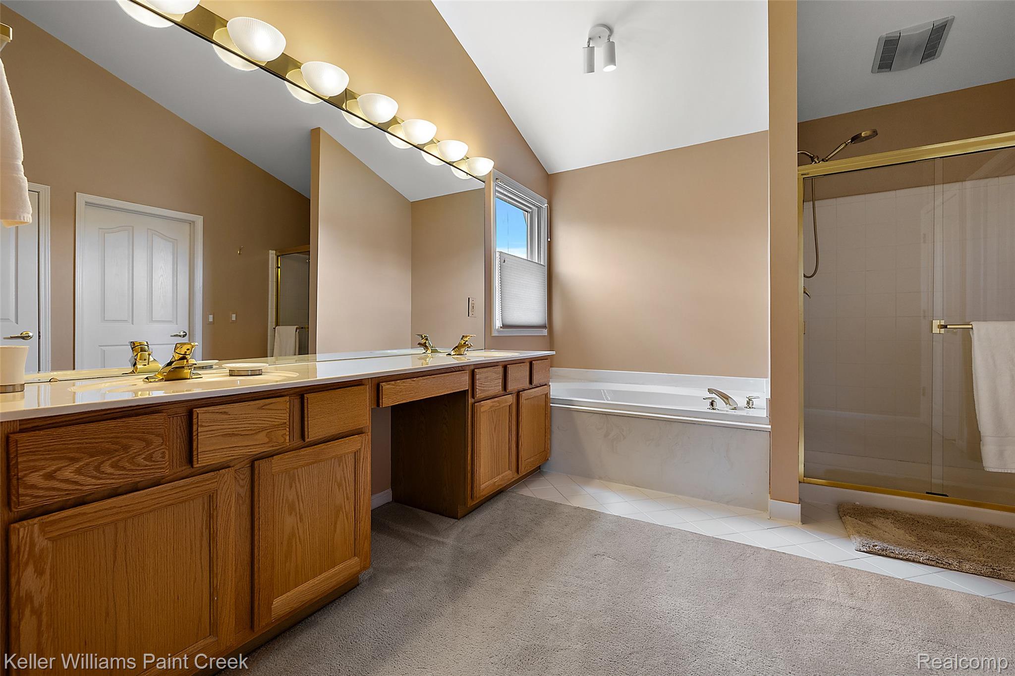 1933 Catlin Drive Rochester, MI 48306 - Photo 29 of 54 Bathroom with a stall shower, double vanity, a garden tub, lofted ceiling, and light tile patterned floors