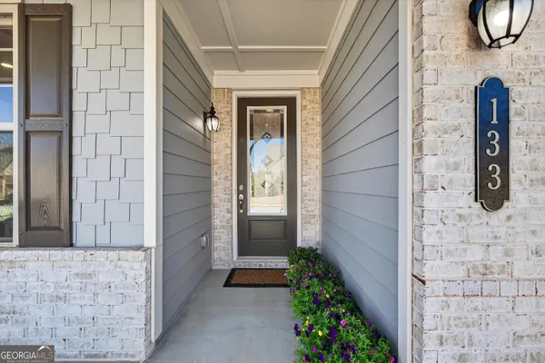 a kitchen with stainless steel appliances white cabinets a sink a stove a refrigerator and chairs