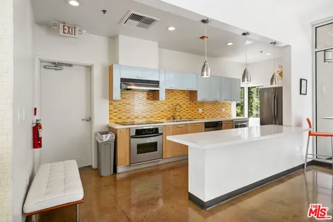 a large kitchen with stainless steel appliances kitchen island granite countertop a refrigerator and a stove top oven