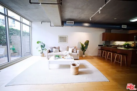 a living room with stainless steel appliances furniture a rug kitchen and a table