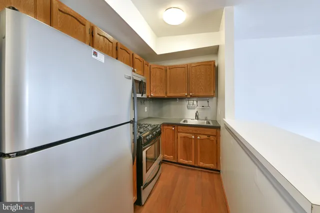 a kitchen with stainless steel appliances a refrigerator a sink and white cabinets