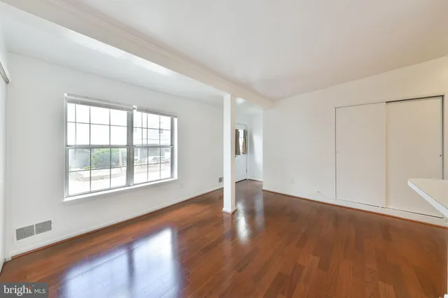 an empty room with wooden floor and windows
