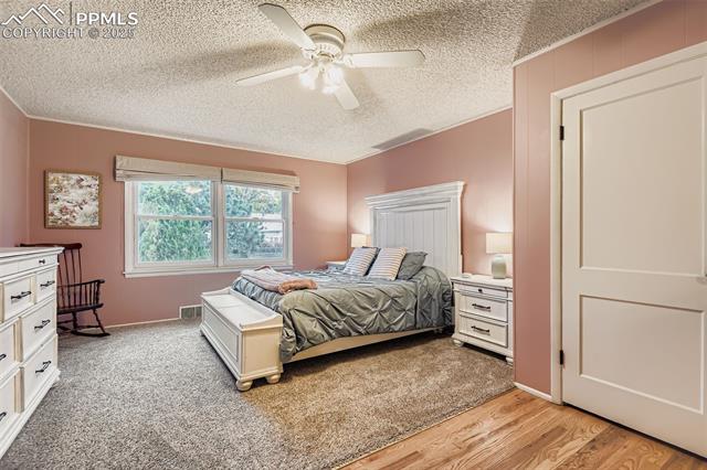 2462 Lafayette Road Colorado Springs, CO 80907 - Photo 16 of 22 Bedroom featuring a ceiling fan, light wood finished floors, a textured ceiling, and light carpet