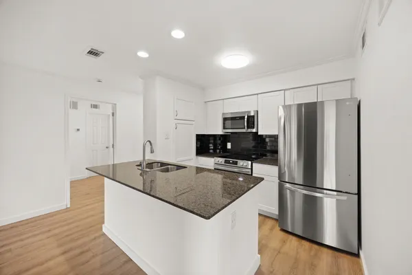 a kitchen with kitchen island granite countertop a stove top oven a sink and a granite counter tops