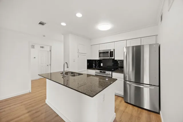 a kitchen with kitchen island a counter top space cabinets and stainless steel appliances