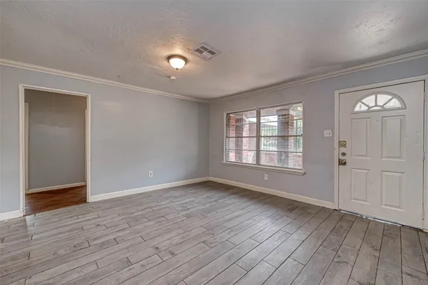 a view of an empty room with wooden floor and a window