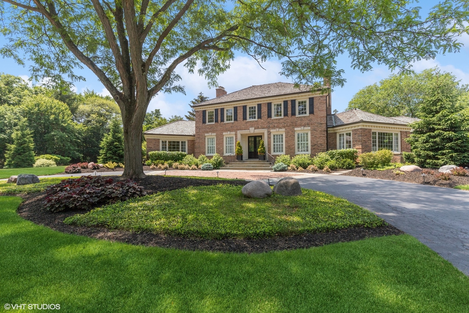 a front view of a house with a garden and trees