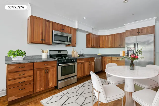 a view of patio with chairs and table under an umbrella with potted plants