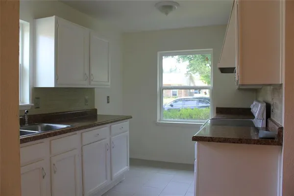 a kitchen with granite countertop a sink a stove and a window
