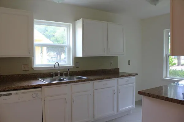 a kitchen with granite countertop a sink and white cabinets