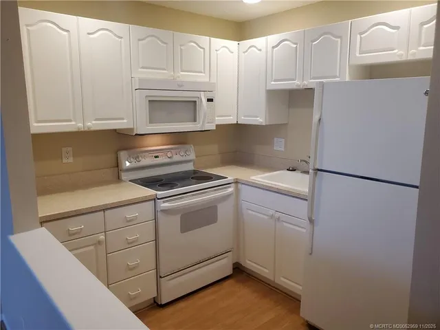 a kitchen with white cabinets and white appliances