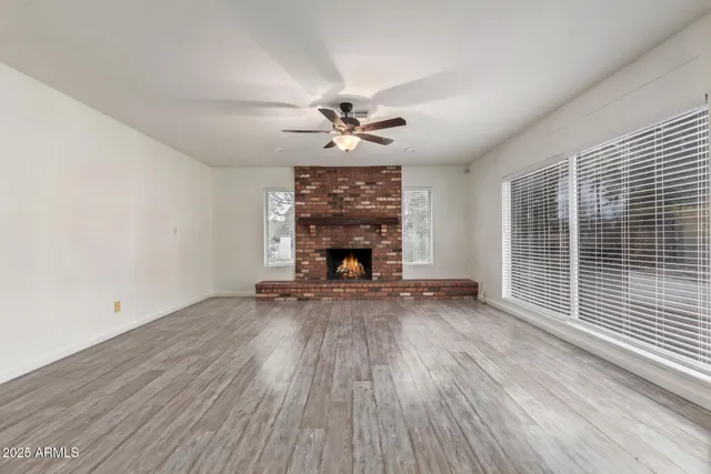 an empty room with windows fireplace and a wooden floor