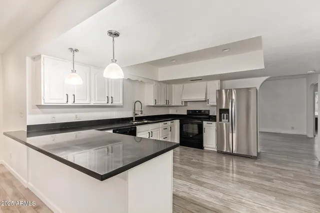 a kitchen with stainless steel appliances granite countertop a sink a stove and a refrigerator