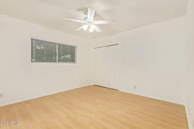 an empty room with a chandelier fan and windows
