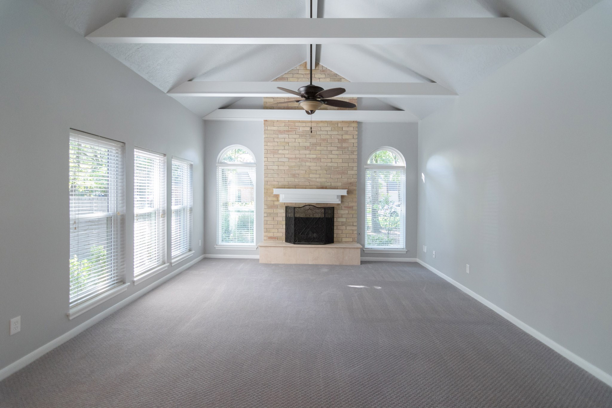 10 Coralvine Court Spring, TX 77380 - Photo 9 of 34 Gorgeous living room has cathedral ceilings with exposed beams, brick fireplace and expansive windows for natural lighting.
