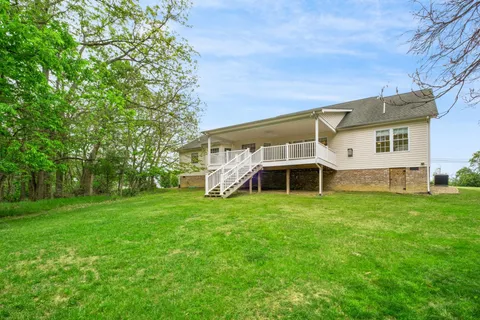 a view of a house with a big yard and large trees