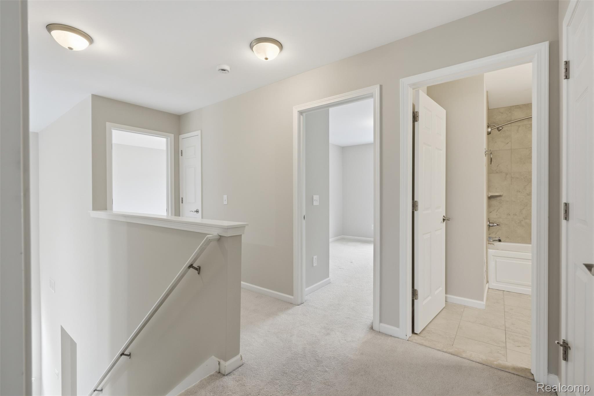 41594 Mitchell Road Novi, MI 48377 - Photo 15 of 35 Hall with an upstairs landing, light carpet, and light tile patterned floors