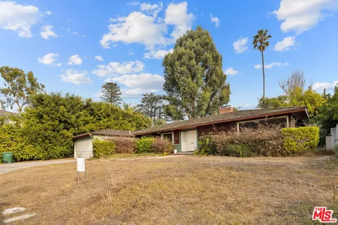 a front view of a house with a yard and trees