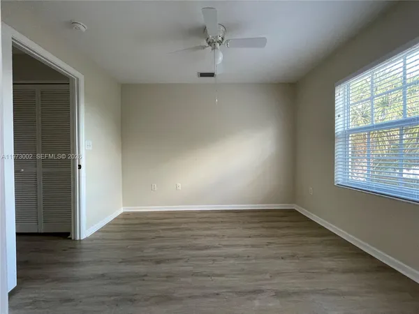 an empty room with wooden floor cabinet and windows