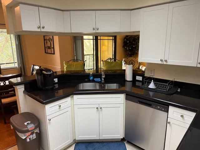 a kitchen with granite countertop a sink a stove and cabinets