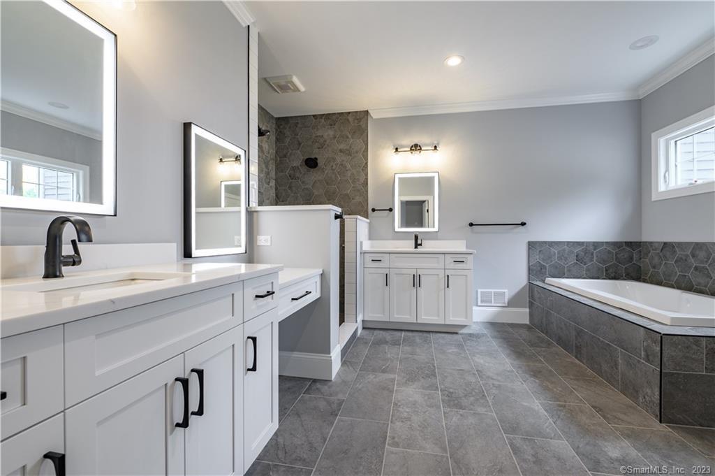 a spacious bathroom with a vanity a sink a mirror a bathtub and window