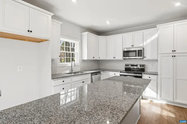 a kitchen with granite countertop a stove a sink and a refrigerator