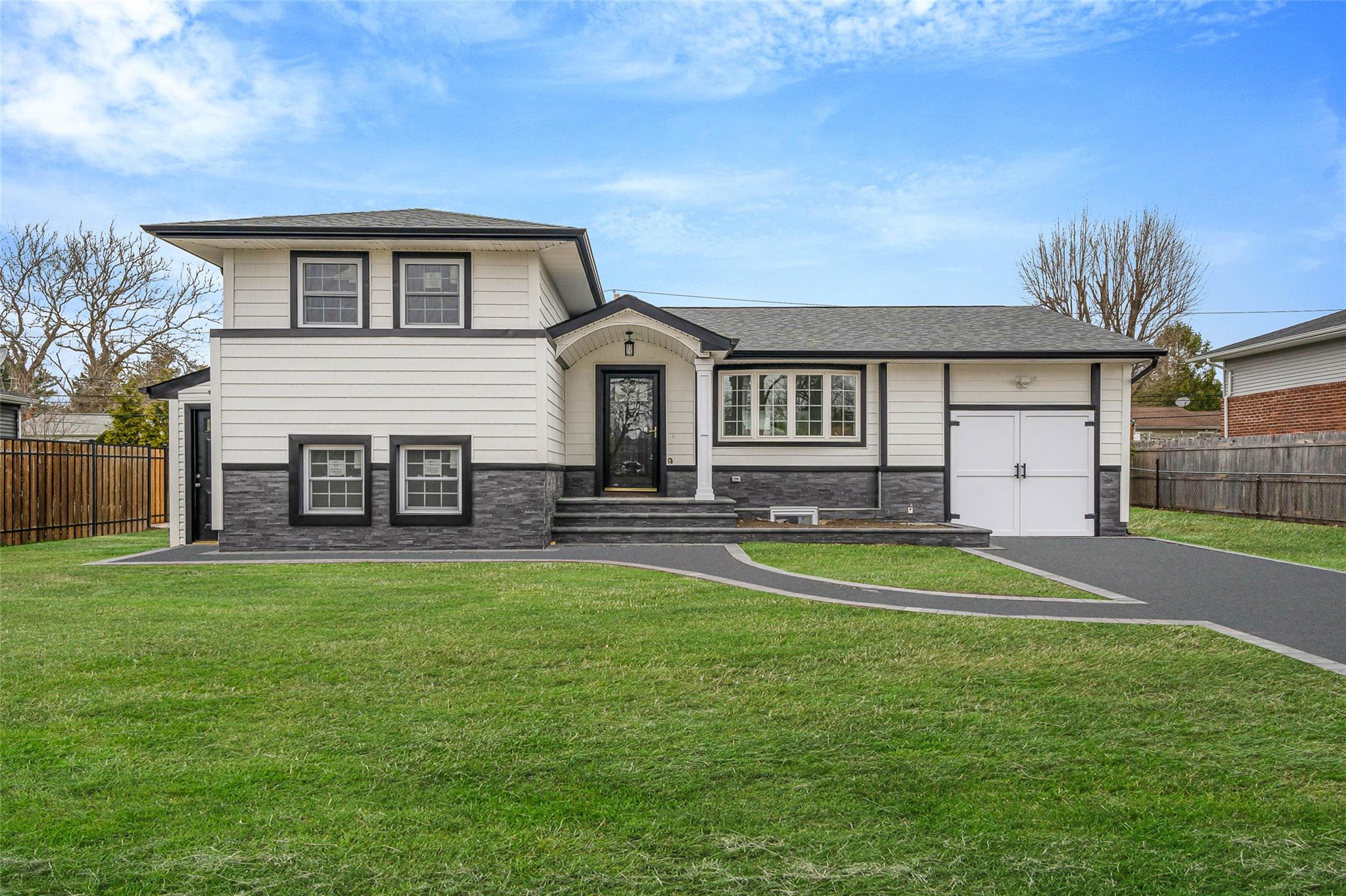 9 Delaware Avenue Commack, NY 11725 - Photo 1 of 1 Tri-level home featuring a front lawn, driveway, stone siding, and fence