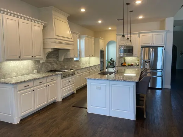 a kitchen with stainless steel appliances granite countertop a sink a stove and a refrigerator
