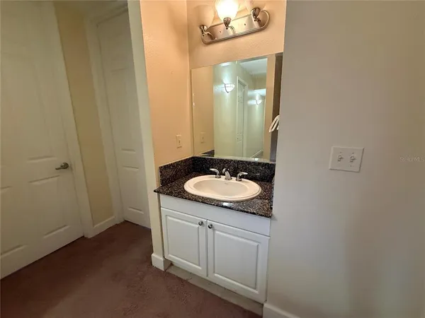 a bathroom with a granite countertop sink and a mirror