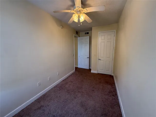an empty room with a chandelier fan and closet