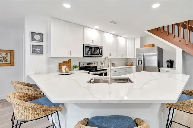 a kitchen with stainless steel appliances kitchen island granite countertop a sink and a refrigerator