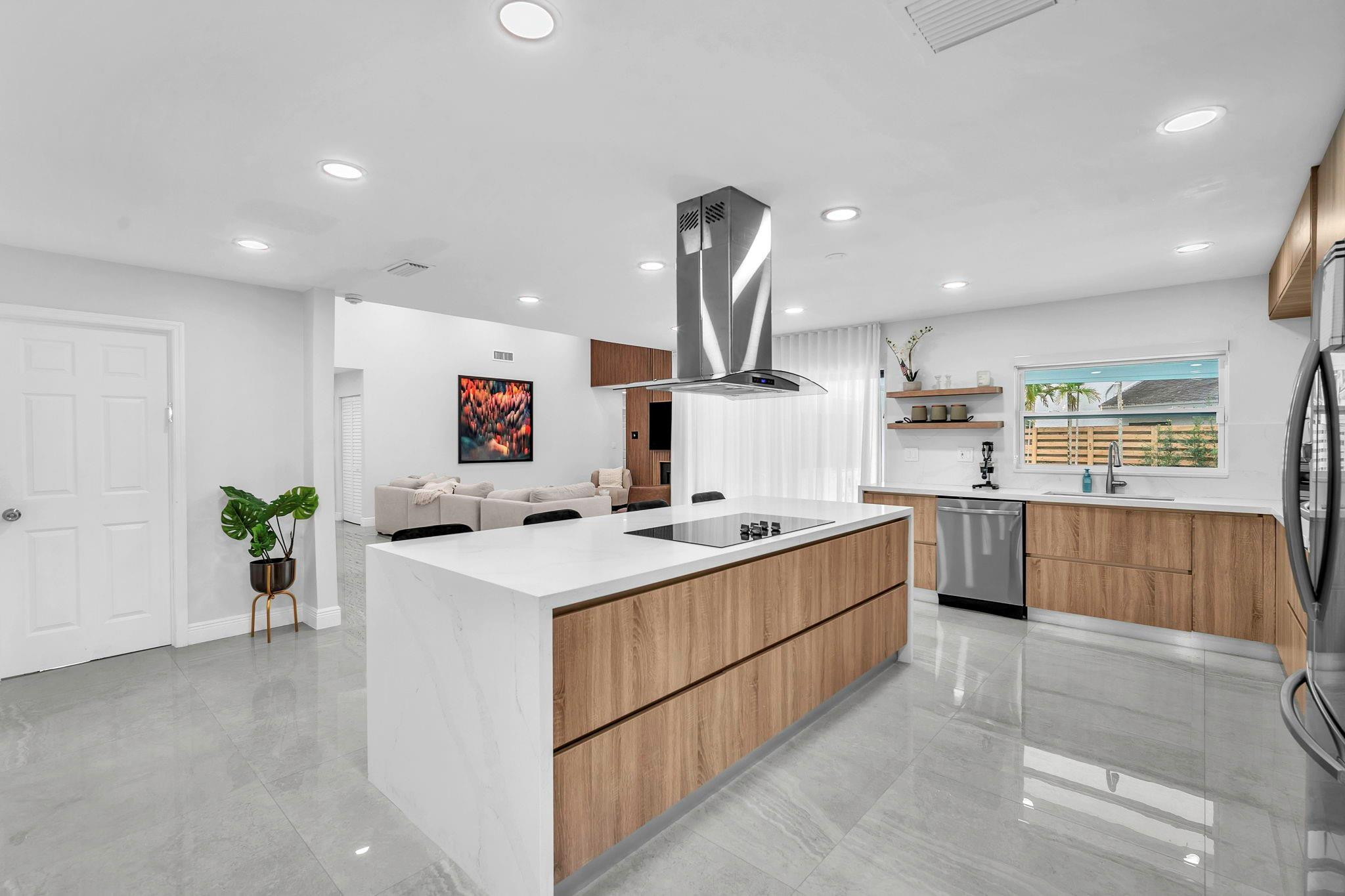 136 Greens Road Hollywood, FL 33021 - Photo 11 of 32 a kitchen that has a lot of cabinets in it and wooden floors