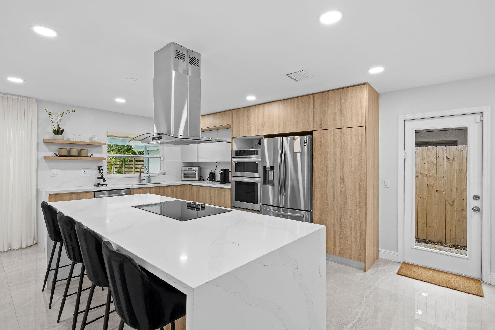 136 Greens Road Hollywood, FL 33021 - Photo 12 of 32 a kitchen with stainless steel appliances a kitchen island a stove a table and chairs