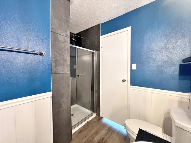 an empty room with wooden floor a ceiling fan and windows