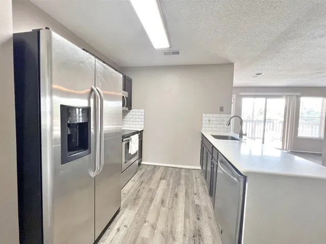 a kitchen with stainless steel appliances kitchen island sink refrigerator and stove