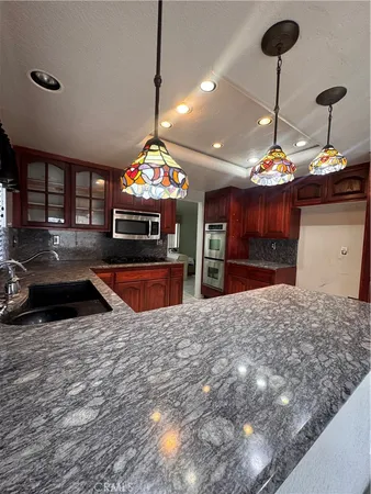 a kitchen with stainless steel appliances granite countertop a sink a stove and a wooden cabinets