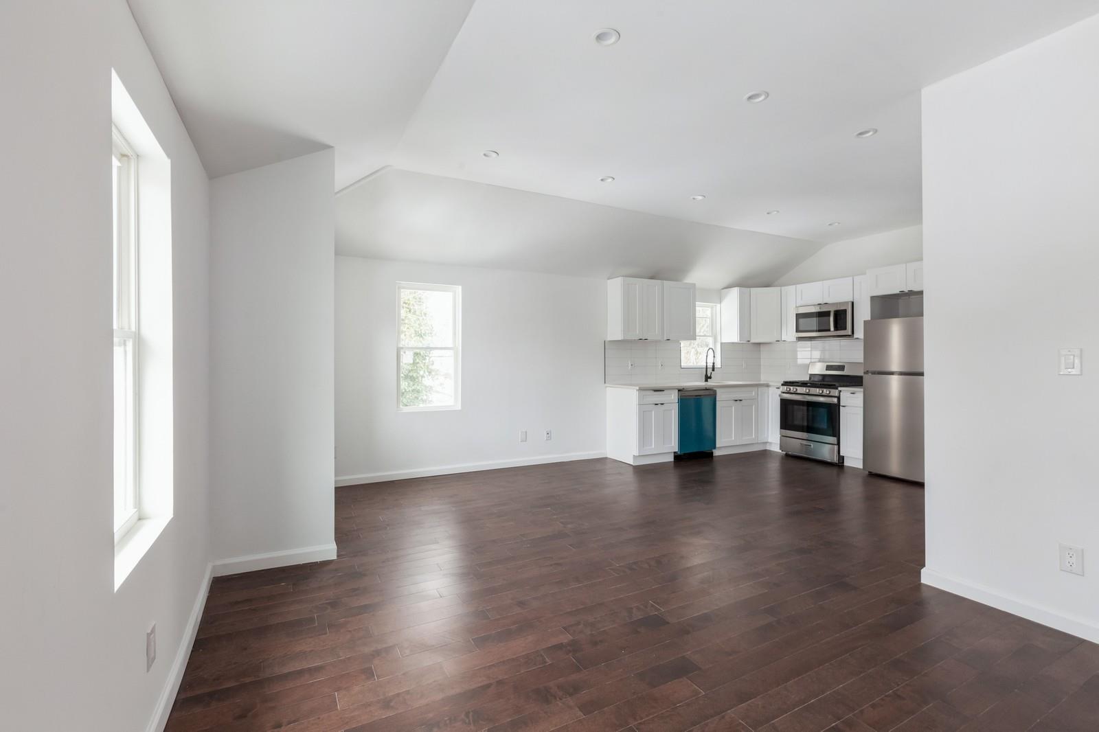 100-03 90th Avenue Queens, NY 11418 - Photo 11 of 18 Unfurnished living room with baseboards, lofted ceiling, and dark wood-type flooring