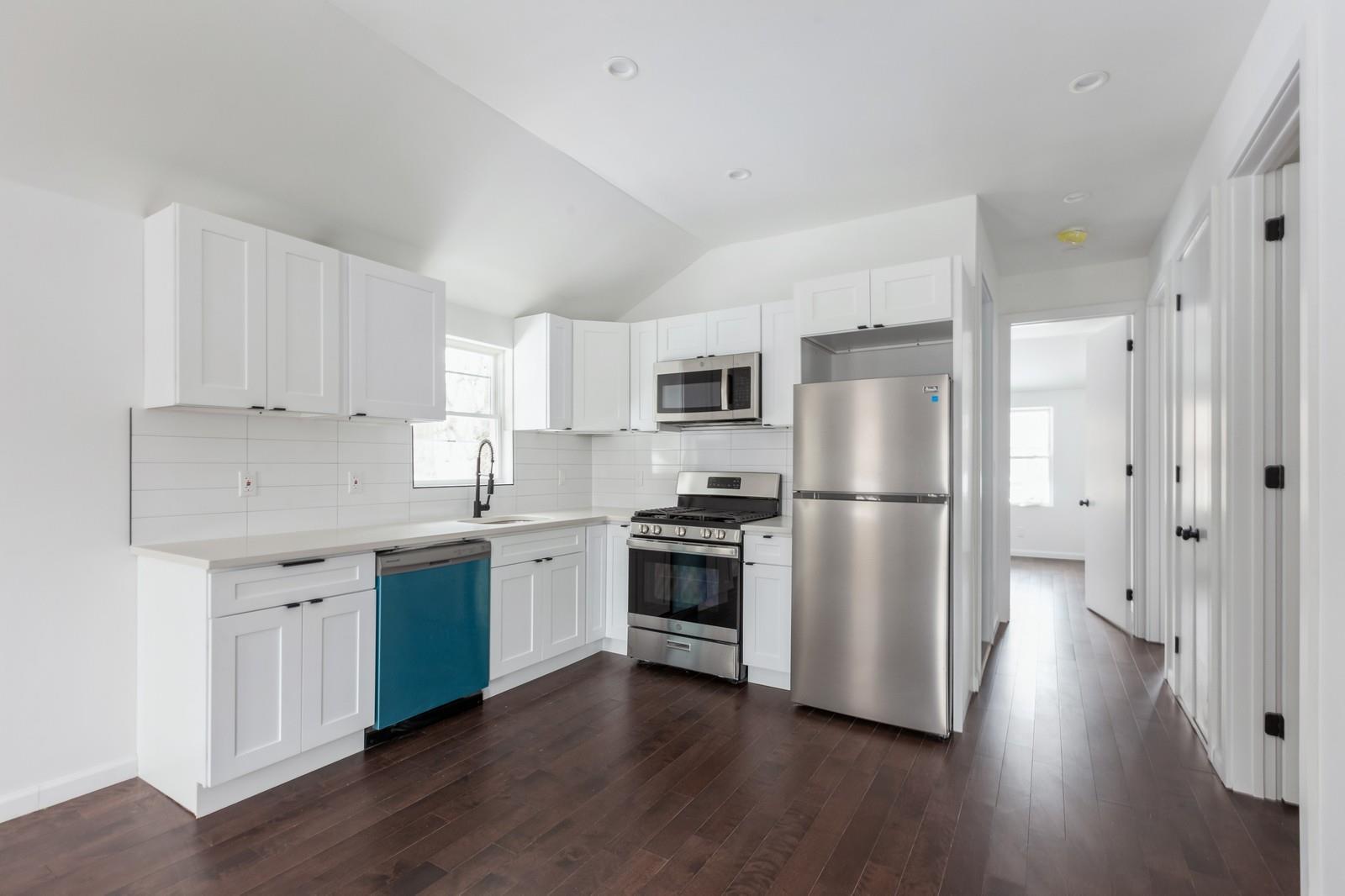 100-03 90th Avenue Queens, NY 11418 - Photo 13 of 18 Kitchen with dark wood finished floors, a wealth of natural light, appliances with stainless steel finishes, and decorative backsplash