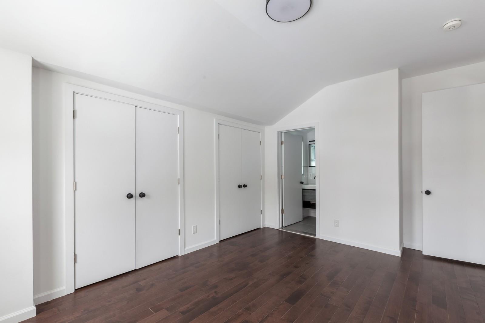 100-03 90th Avenue Queens, NY 11418 - Photo 15 of 18 Unfurnished bedroom with vaulted ceiling, baseboards, multiple closets, dark wood finished floors, and ensuite bathroom