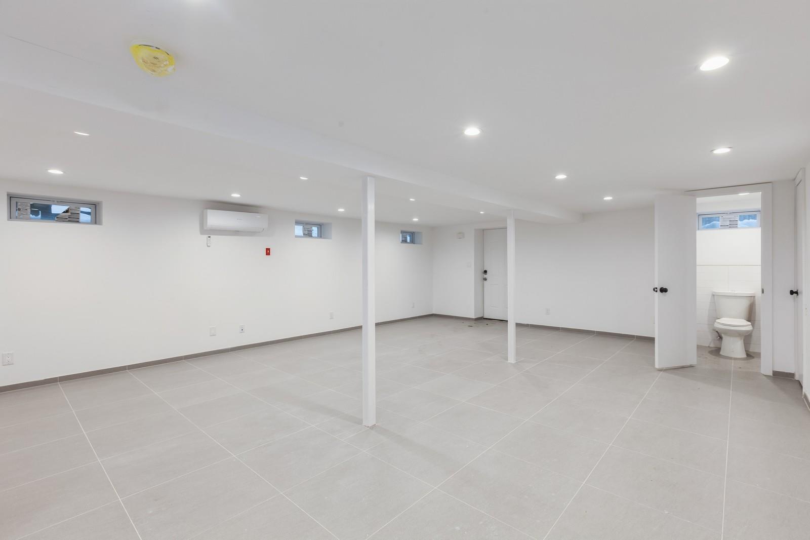 100-03 90th Avenue Queens, NY 11418 - Photo 16 of 18 Basement with baseboards, a wall unit AC, recessed lighting, and light tile patterned floors