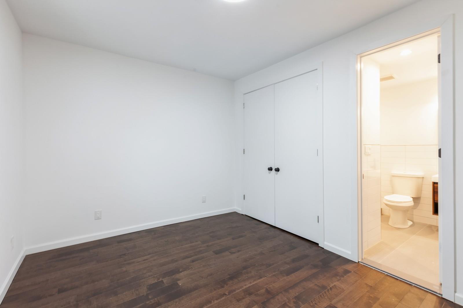 100-03 90th Avenue Queens, NY 11418 - Photo 8 of 18 Unfurnished bedroom featuring tile walls, dark wood-style flooring, baseboards, connected bathroom, and a closet