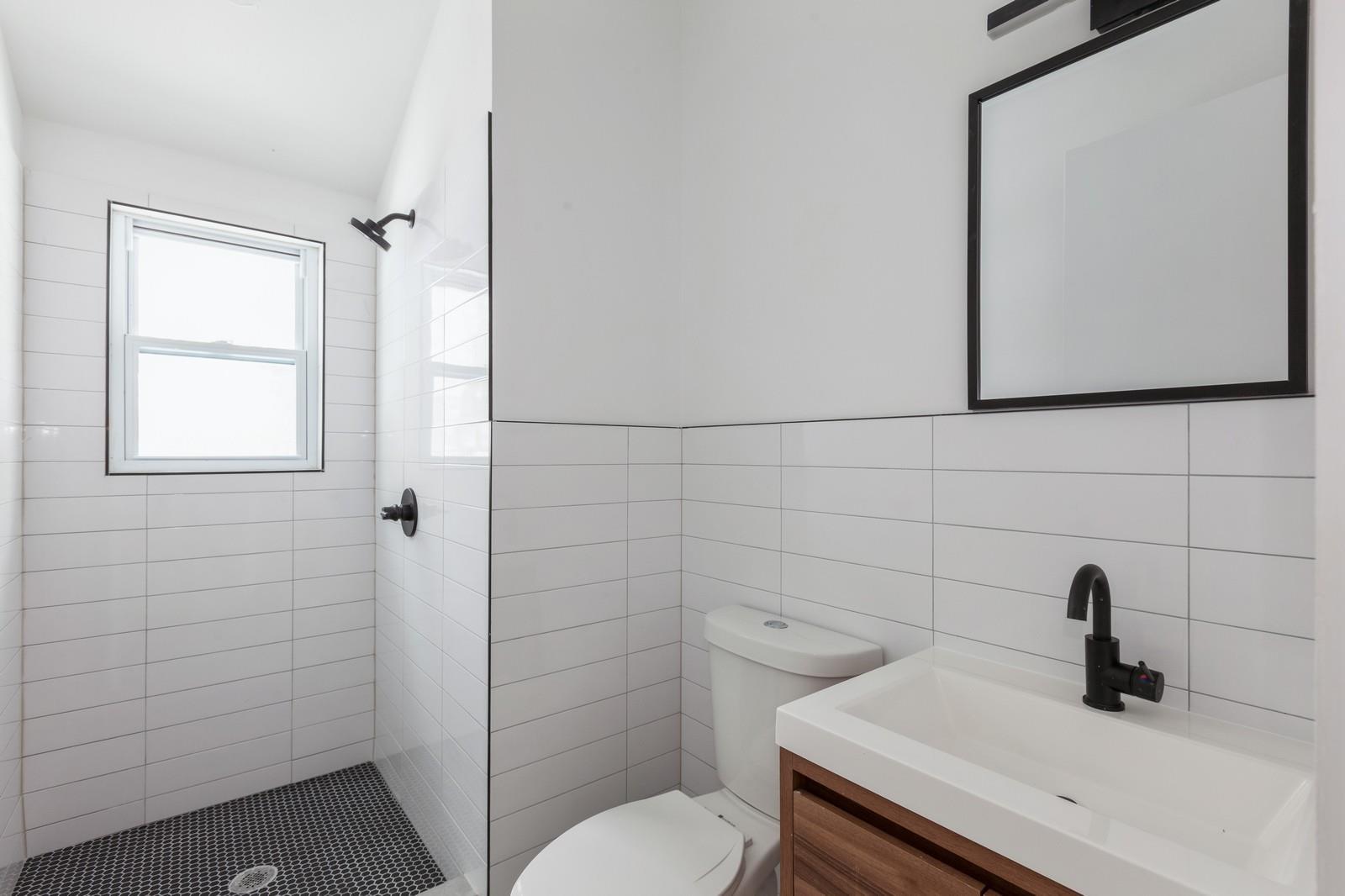 100-03 90th Avenue Queens, NY 11418 - Photo 9 of 18 Bathroom featuring tile walls, vanity, toilet, and tiled shower