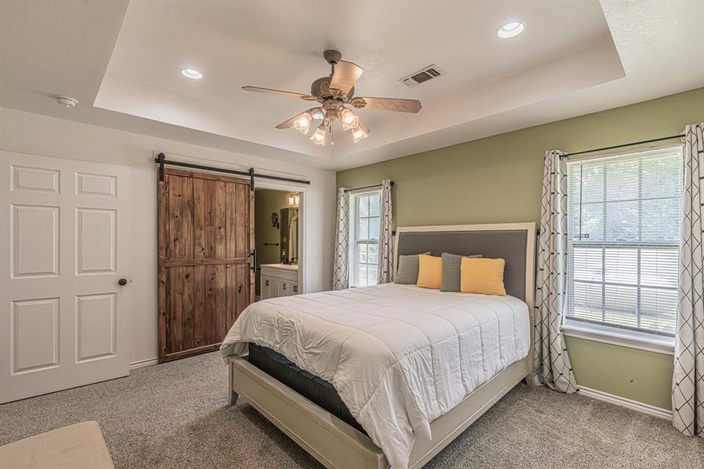204 Spring Branch Trail South Springtown, TX 76082 - Photo 25 of 39 Recessed lighting and ceiling fan above, dual windows with blinds, a white six-panel door, and a rustic wood-finish barn door
