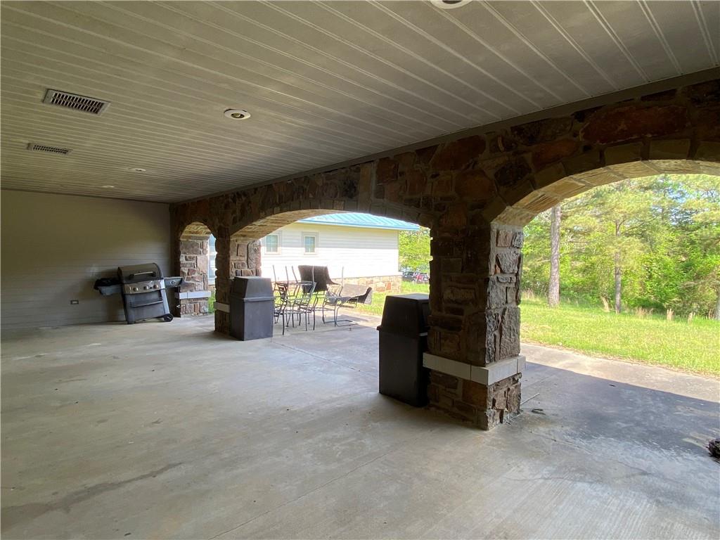 8524 Youth Ranch Road Mulberry, AR 72947 - Photo 9 of 40 Spacious covered patio featuring stone arches, concrete flooring, recessed lighting, and a wood-finish ceiling