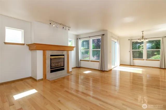an empty room with wooden floor fireplace and windows