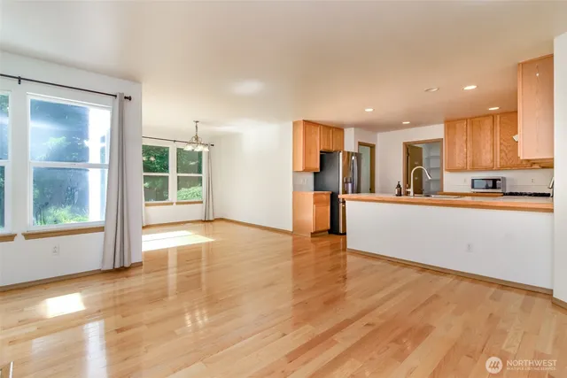 a view of a kitchen with kitchen island a window wooden floor and stainless steel appliances